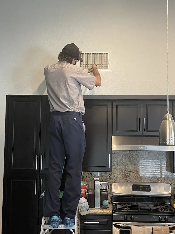 Technician inspecting an air vent during HVAC service in Manhattan Beach